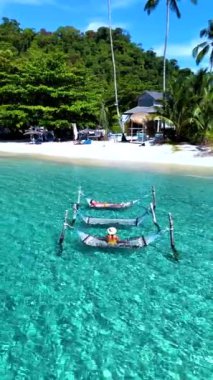 Bir çift, Koh Kood Tayland 'ın berrak sularında asılı duran hamakların keyfini çıkarıyor. Güzel beyaz kumsal ve canlı yeşillik mükemmel bir tropikal kaçış yaratır..