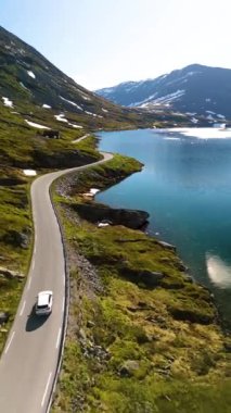 Parlak mavi bir gökyüzü altında görkemli dağlar ve yemyeşil yeşilliklerle çevrili sakin bir fiyordun yanında dönen bir araba gibi büyüleyici güzellikleri keşfedin. Langvatnet Geiranger Norveç