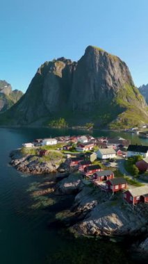 Norveç 'te renkli evlerin kayalık kıyı şeridi boyunca uzanan yüksek bir dağ zeminine karşı uzandığı bir sahil köyünün görkemli cazibesini keşfedin. Hamnoy Lofoten