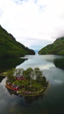 Dik kayalıkların arasında küçük bir ada, yemyeşil ve sakin sularla çevrili büyüleyici kırmızı kulübeler sergiliyor. Lovrafjorden Norveç