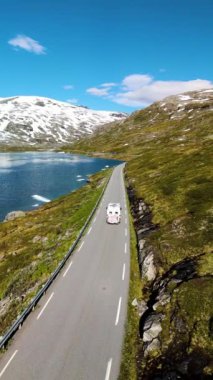 Norveç 'in güzelliğini keşfedin. Maceraperest bir karavan sakin sular ve görkemli dağlardan geçen pitoresk bir yolda ilerliyor. Doğayı en iyi şekilde tecrübe et. Langvatnet Geiranger Norveç