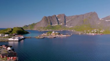 Norveç 'teki görkemli dağların arasına kurulmuş geleneksel bir balıkçı köyünün göz kamaştırıcı manzaralarını keşfedin. Deneyim doğası sükunet ve canlı renkler suya yansıyor. Lofoten Norveç