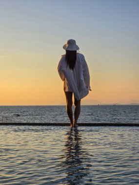 Koh Munnork Adası 'nda bir siluetin suyun kenarında durduğu, canlı bir günbatımının ılık parıltısıyla yıkandığı sakin bir an..