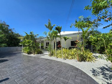 Yeşillik içinde, bu büyüleyici tropikal inziva güzel beton yollarla övünüyor. Canlı manzara, modern bir aile evi olan Tayland banliyö bölgesinin huzurlu atmosferini yükseltiyor.