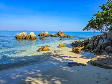 Tayland, Rayong 'daki Koh Munnork Adası' ndaki pürüzsüz kumlu plajlarda kristal berraklığında sular dolaşır. Güneş, kayaların üzerine yumuşak gölgeler bırakır. Rahatlamak için mükemmel bir cennet yaratır..