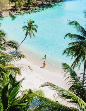 Koh Kood 'un yumuşak, beyaz kumları boyunca sallanan palmiyelerle çevrili iki figür yavaşça yürüyor. Kristal berrak sular, batan güneşin sıcak ışığında parlıyor..