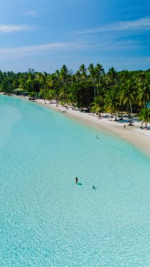 Tayland, Koh Kood 'da el değmemiş beyaz kumlara yumuşak turkuaz dalgalar çarpar. Güneş ışığı suda dans ederken ziyaretçiler yemyeşil yemyeşil bu tropik cennetin huzurlu güzelliğinin tadını çıkarıyorlar..