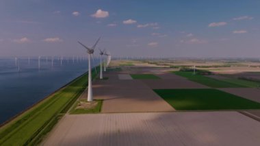 Hollanda kırsalında zarifçe dönen yel değirmeni türbinlerinin güzelliğini hissedin. Bu muhteşem yapılar, verimli alanlar ve sakin sularla çevrili yenilenebilir enerjiyi kullanırlar..