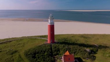 Teksas deniz fenerinin nefes kesici manzarasını deneyimleyin. Hollanda, Texel adasında dimdik ayakta duruyor. Bu çarpıcı manzara huzurlu sahil şeridi ve kumlu plajların panoramik manzarasını sunar..