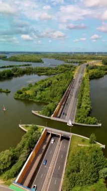 Araçların Hollanda 'daki sakin bir su yolunda seyahat ettiği büyüleyici bir mühendislik harikası olan Veluwemeer Su kemerini keşfedin. Hollanda 'daki otoyolun üstündeki gölde su kemeri.