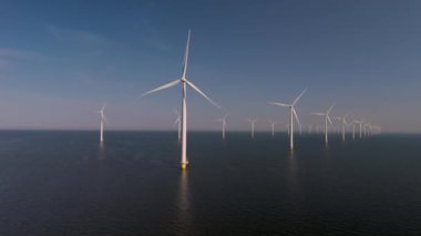 Hollanda 'nın sakin sularında çarpıcı bir rüzgar türbini görüntüsü yüksekte duruyor. Okyanustaki yel değirmeni parkı, yel değirmeni türbinlerinin yeşil enerji üreten hava aracı görüntüsü.