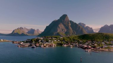 Norveç 'in görkemli dağlarla sakin sular arasında yuva yapmış pitoresk bir kıyı köyünü keşfedin. Güneş parıldıyor, Reine köyü Lofoten