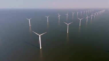 Sakin sularda rüzgarın gücünü yakalayan çarpıcı bir rüzgar türbini dizisi yüksekte duruyor. Bu pitoresk dekor Hollanda 'da sürdürülebilir enerji üretimini gösteriyor.