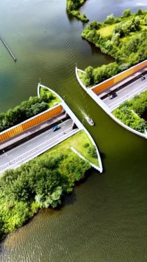 Veluwemeer Aqueduct 'ta dolaşırken, Hollanda' daki yemyeşil yemyeşil sularla çevrili yolun zarif bir şekilde su altından geçtiği şaşırtıcı mimari tasarıma hayret ediyorum..