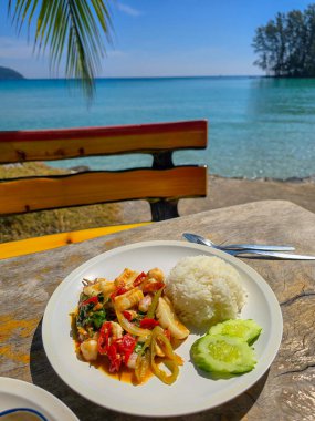 Parlak renkler tabağı mis kokulu pirincin yanında servis edilen yerel lezzetlerin hoş bir karışımıyla doldurur. Koh Kood 'un berrak sularının barışçıl manzarası bu aşçılık deneyimini güçlendiriyor. Phat kaphrao Thai yemeği