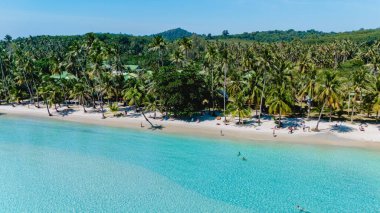 Kristal berrak sular nazikçe Koh Kood, Tayland 'ın yumuşak kumlu kıyılarına çarpar. Güneş ışığı dalgaların üzerinde dans eder palmiye ağaçları ılık bir tropikal esintide sallanırken dinlenmeye ve maceraya davetiye çıkarır..