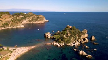 Dalgalar açık mavi gökyüzünün altında yavaşça kıyıya vururken, Taormina 'nın altın kumlarında rahatlayın. Sicilya kıyı şeridinin dingin güzelliğini tecrübe edin, kayıklar ve yemyeşil ile benekli..