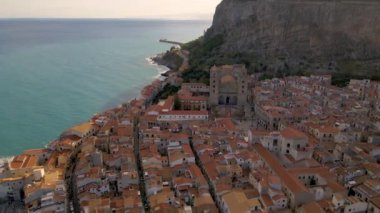Sicilya kıyı manzaralarının büyüleyici güzelliğini keşfedin. Güneş büyüleyici bir kasabanın üzerinde batıyor. Terracotta çatıları canlı mavi denize karşı parıldıyor, Cefalu Sicilya