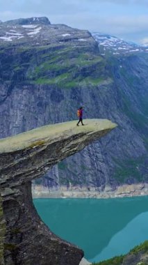 Yalnız bir maceracı, nefes kesici Trolltunga Norveç manzaralarıyla çevrili, çarpıcı bir uçurum kenarında duruyor..
