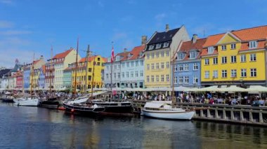 Kopenhag Danimarka 20 Temmuz 2024 'te, tarihi Nyhavn Limanı' nı çevreleyen parlak binalar, canlı atmosferin tadını çıkaran ziyaretçilerle doludur..