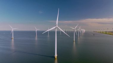 Dev yel değirmeni türbinleri Hollanda 'daki yenilenebilir enerjiyi kullanarak sakin sularda zarifçe dönüyor. Olağanüstü bir manzara doğa ve teknoloji arasındaki uyumu sergiliyor..