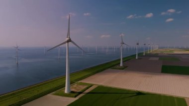 Hollanda 'da mavi gökyüzüne karşı dimdik duran çarpıcı bir yeldeğirmeni türbini dizisi keşfedin. Bu büyüleyici görüntü doğayla uyum içinde yenilenebilir enerji sergiliyor..