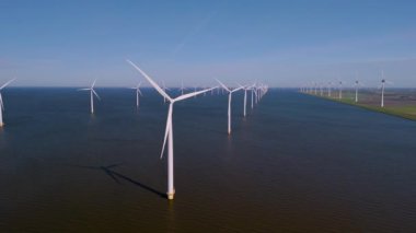 Hollanda 'nın sakin sularına karşı dimdik duran devasa yel değirmeni türbinleri rüzgârın gücünü zarafetle ele geçiriyor. Bu çarpıcı manzara teknoloji ve doğanın uyumunu gösteriyor..