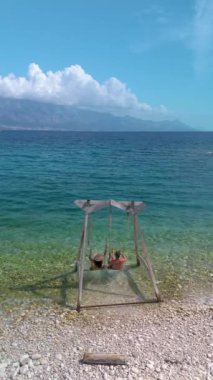İki kişi, Brac Island Hırvatistan 'ın berrak, masmavi sularında sallanan huzurlu bir anın tadını çıkarıyor. Güzel manzara yumuşak dalgaları ve parlak bir gökyüzünün altında uzak dağları barındırır..