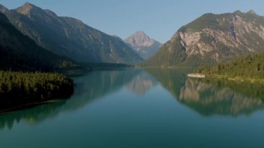 Güne, sakin suların berrak gökyüzünün altındaki görkemli dağları yansıttığı Avusturya 'daki çarpıcı Plansee Gölü' nde başlayın. Yeşil ormanlar ve engebeli tepelerle çevrili doğa sükunetini keşfedin..