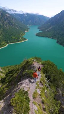 Marvel at the breathtaking views of Plansee Lake in Austria as adventurers hike along picturesque trails. The vibrant turquoise waters and lush landscapes create an unforgettable experience.