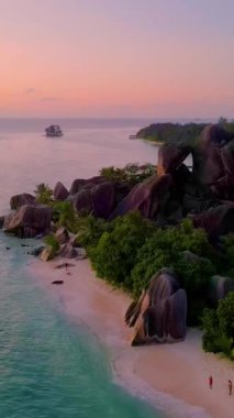 Güneş Seyşeller 'in üzerinde batarken Anse Source DArgent La Digue doğal güzelliği. Yumuşak dalgalar, görkemli granit kayalar ve yemyeşil kayalar tarafından çerçevelenmiş tenha kumlu kıyılara çarpar.