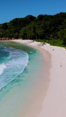 Ziyaretçiler, sıcak güneş ve yumuşak kumun tadını çıkararak, La Digue Seyşeller 'in canlı kıyı şeridi boyunca yürürler. Turkuaz sular el değmemiş plajda yavaşça tur atar ve dingin bir atmosfer yaratır..