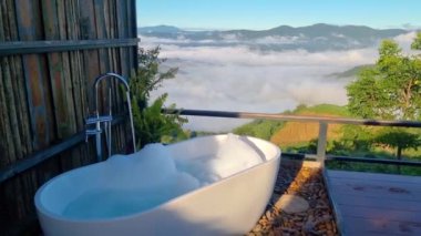 Chiang Mai, Tayland 'ın yemyeşil dağlarına bakan çarpıcı bir açık hava banyosu deneyimi. Yumuşak sis ve doğa güzelliğinin ortasındaki dingin atmosferin tadını çıkar..