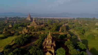 Myanmar, Bagan 'ın nefes kesici manzarasını keşfedin. Eski pagodaların yemyeşil topraklar arasında görkemli bir şekilde yükseldiği yer. Gün doğumunda bu tarihi yerin huzur dolu güzelliğini tecrübe edin..