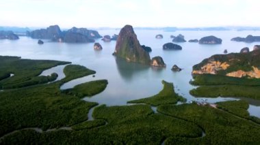 Güneş çarpıcı kireçtaşı oluşumlarının ardında batarken Phangnga Körfezi Tayland 'ın nefes kesici güzelliğine tanık olun. Sakin sular akşam gökyüzünün canlı renklerini yansıtır.