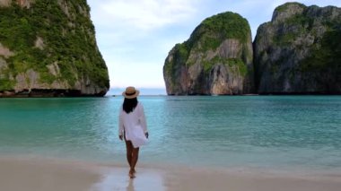 Koh Phi Phi Adası 'nın kumlu kıyılarında yürüyen Krabi Tayland' da güneş ışıldarken bir huzur hissi hakim. Yüksek uçurumlar çarpıcı bir zemin oluşturur.,