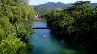 Kanocular Koh Chang Tayland 'ın sakin sularında süzülüyor, canlı yeşillikler ve dağlık arka planlarla çevrili. Bu tropikal orman cennetinde doğanın güzelliğini hissedin..