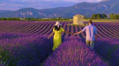 Güneş batarken, Fransa 'nın Provence kentindeki canlı lavanta tarlalarında el ele yürüyen bir çift manzara üzerinde altın renkler sergiliyor. Hava romantizm ve sükunetle dolu..