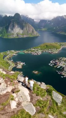 Dağların sakin sularla buluştuğu yüksek bir noktadan Norveç arazisi. Bu pitoresk dekor canlı yeşillikler ve aşağıdaki tuhaf sahil kasabasını gösteriyor. Reinebringen yürüyüşü Lofoten Norveç