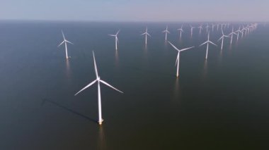 Havadan bakıldığında sakin sulara yerleştirilmiş geniş bir yeldeğirmeni türbinleri görülüyor. Okyanustaki yel değirmeni parkı, Hollanda 'da yeşil enerji üreten yel değirmeni türbinlerinin insansız hava aracı görüntüsü.