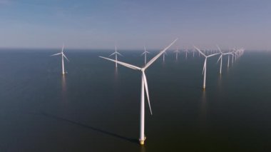 Görkemli yel değirmeni türbinleri Hollanda 'nın sakin sularında dimdik ayakta duruyor ve çarpıcı bir manzara yaratırken yenilenebilir enerjiyi kullanıyorlar. Bıçaklar rüzgarda zarif bir şekilde dönüyor..