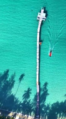 Tayland, Koh Kood 'un büyüleyici güzelliğini keşfedin çarpıcı turkuaz suları ve uzun ahşap iskelede. Dalgalı palmiyeler ve el değmemiş plajlar arasında huzurlu bir tekne yolculuğunun tadını çıkar..