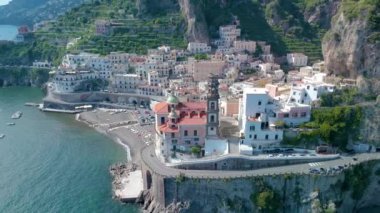 İtalya 'nın Amalfi kentinin güzelliğini keşfedin. Parlak mavi denizin üzerindeki kayalıklara yapışmış renkli binalar. Sahilde rahatla ve manzaranın tadını çıkar..