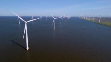 Yel değirmeni türbinleri serin suların üzerindeki meltemle uyum içinde dönüyor. Bu enerji zengini arazi Hollanda 'da sürdürülebilirliğin bir örneği.