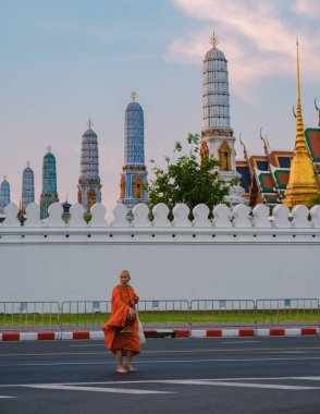 Bangkok Thailand 10 January 2025, a tranquil monk walks gracefully past the ornate spires of the Wat Phra Kaew temple, Grand Royal Palace, showcasing rich cultural heritage. clipart