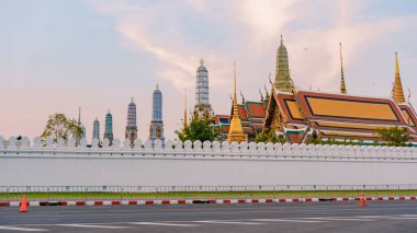 Alacakaranlık sıcacık renklerinin altında Bangkoks tapınaklarının karmaşık kuleleri ve altın çatıları gökyüzüne karşı yükseliyor. Wat Phra Kaew Tapınağı, Büyük Kraliyet Sarayı Bangkok Tayland