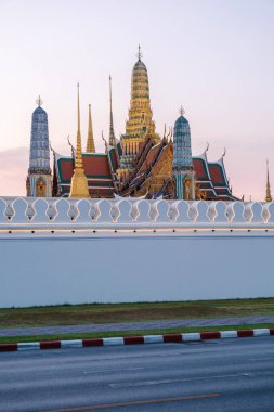 Görkemli altın kuleler Bangkok 'taki alacakaranlık gökyüzünü delip geçiyor, zarif bir mimari sergiliyor. Huzurlu atmosfer, tarih ve güzelliğin bir karışımıyla büyülenir. Wat Phra Kaew Tapınağı, Büyük Kraliyet Sarayı.