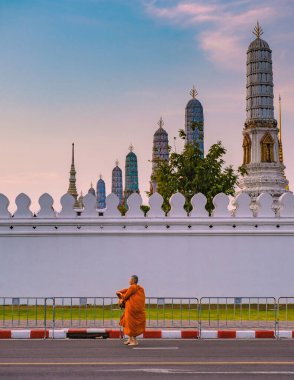 10 Ocak 2025 'te Bangkok Tayland' da, heybetli tapınaklar tarafından çerçevelenmiş sakin bir yolda yürüyen dingin bir keşiş görülüyor. Wat Phra Kaew Tapınağı, Büyük Kraliyet Sarayı
