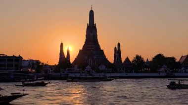 Wat Arun 'un üzerine altın rengi döken büyüleyici günbatımına tanıklık edin. Chao Phraya Nehri' ni yansıtıyor. Bu çarpıcı an, Bangkok mimarisinin alacakaranlıktaki güzelliğini yansıtıyor..
