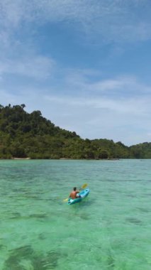 Tayland 'daki Koh Kradan Adası' nın sakin turkuaz sularında süzülürken yemyeşil ve çarpıcı manzaralarla çevrili huzurlu bir kano gezisinin tadını çıkarıyorlar..